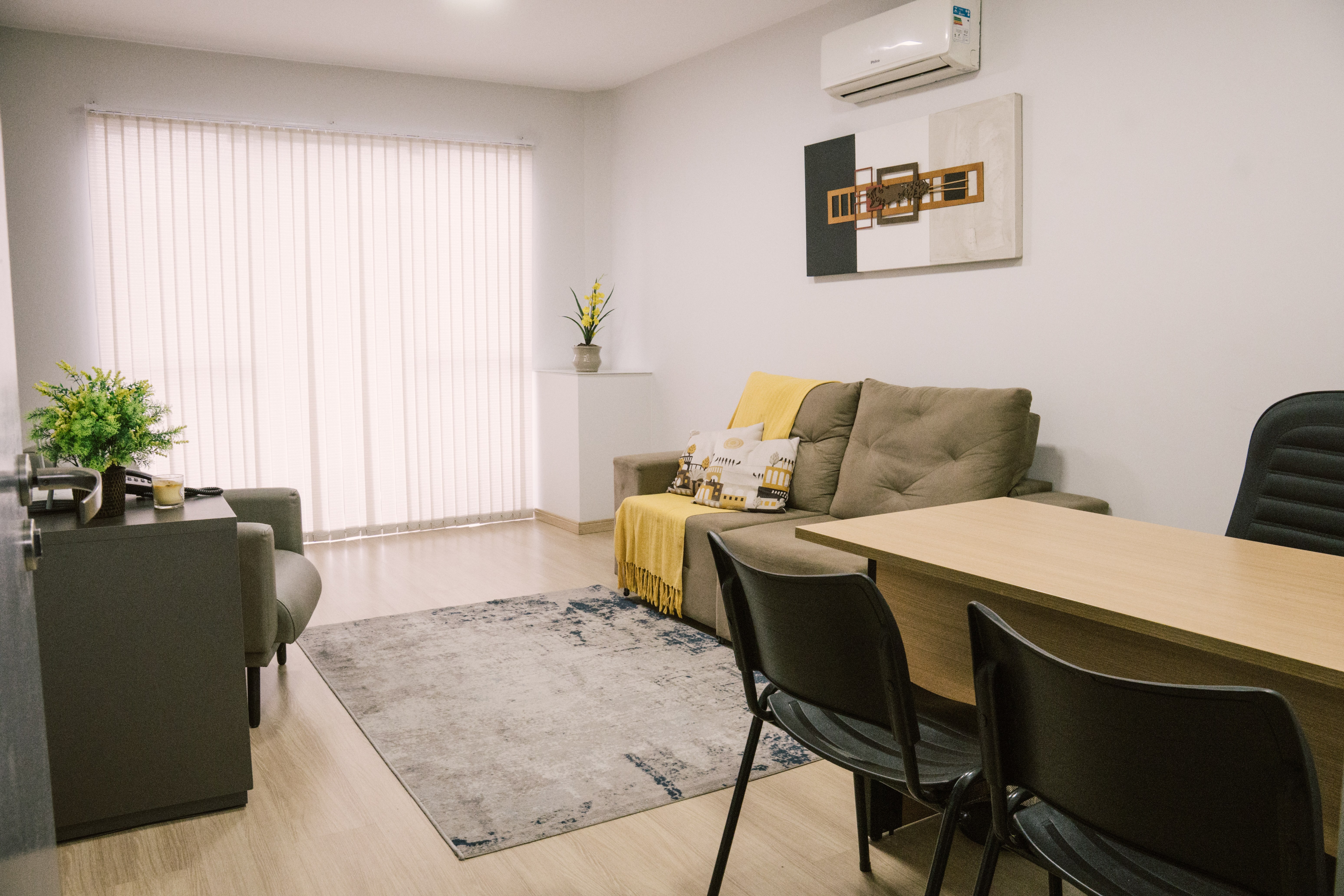 Sala 108 da Willtay com sofá, poltrona, tapete e mesa de trabalho com cadeiras