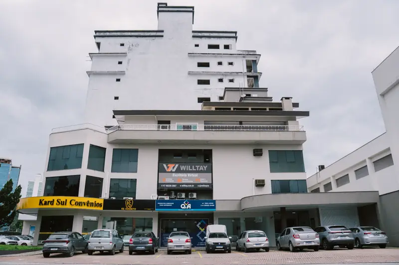 Fachada do prédio da Willtay no Centro de Brusque, com carros estacionados em frente à entrada